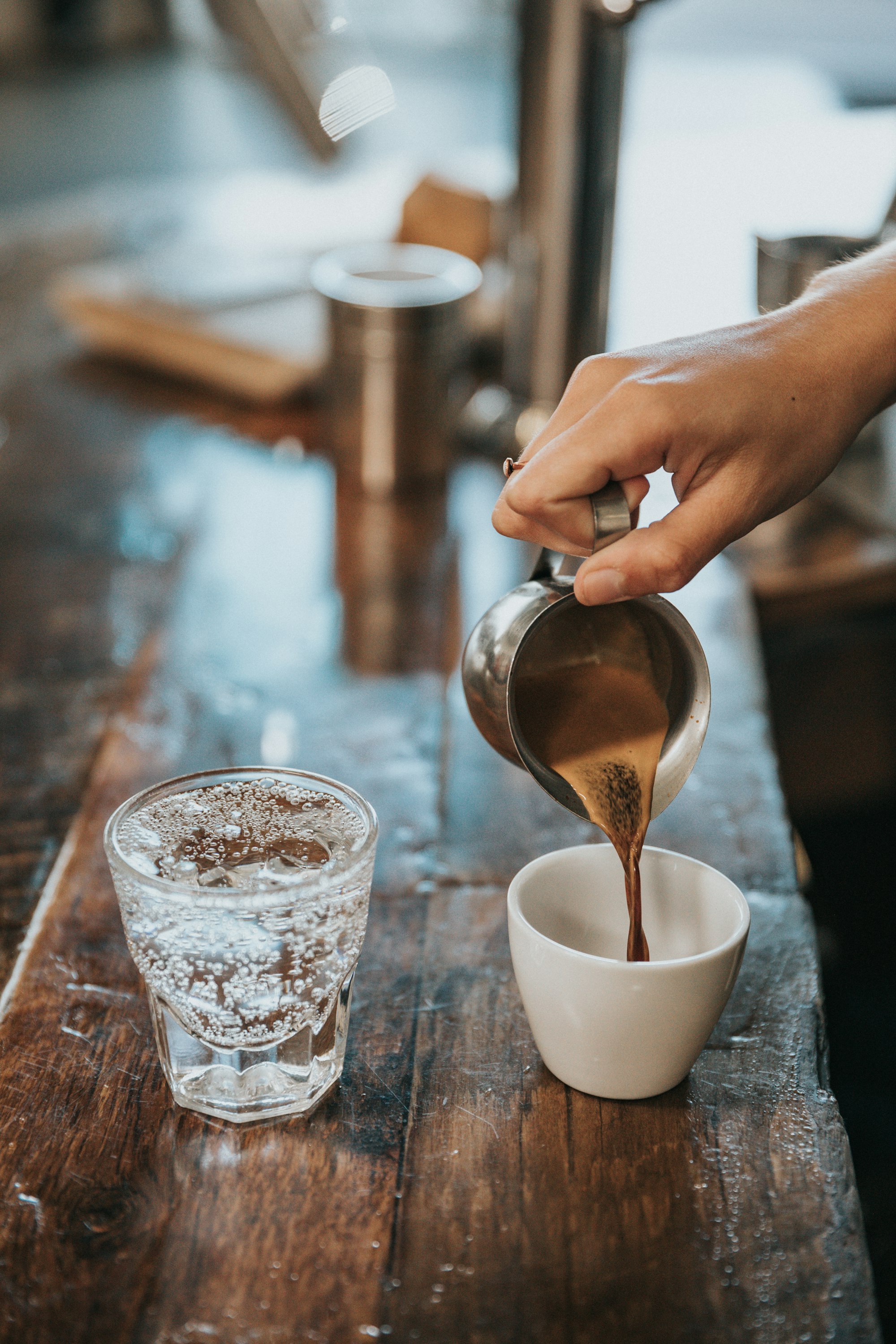 A hand pouring coffee into a glass mug