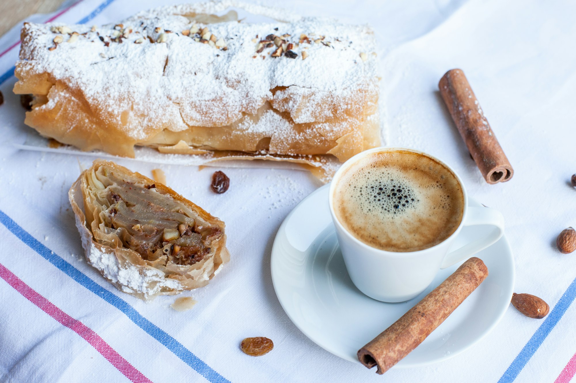 A piece of strudel beside a cup of Viennese coffee